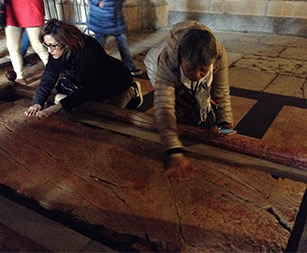 Thelma’s sister, Lourdes, and other pilgrims from Thelma’s pilgrimage group praying at the Stone of Anointing.