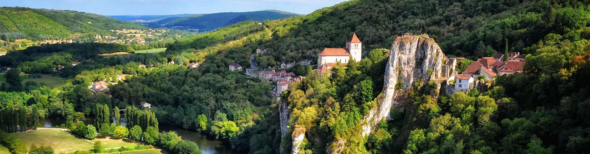 A wide panoramic view of the cliffside village of Saint-Cirq-Lapopie in southern France