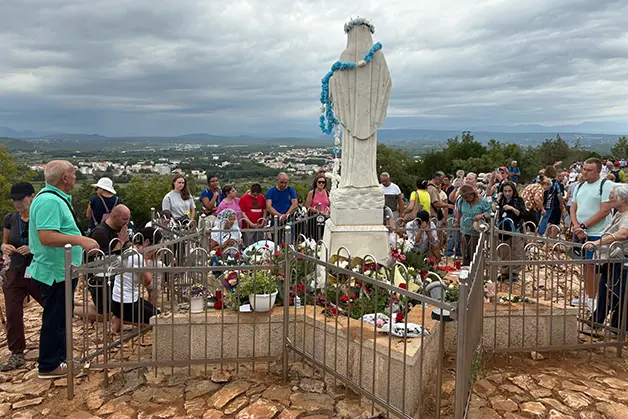 Pilgrims praying at the Queen of Peace statue