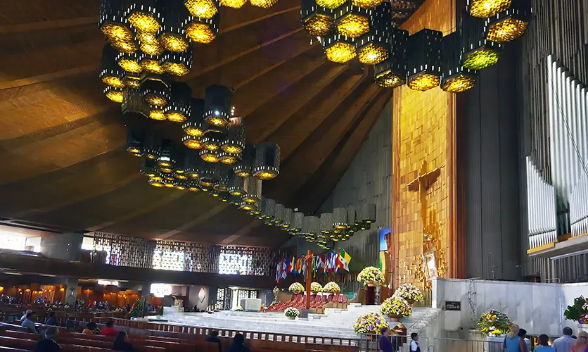 Interior of the modern Basilica of Our Lady of Guadalupe in Mexico City, with the tilma framed on the gold wall above the main altar
