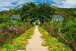 The Grande Allée — a flower-lined pathway beneath rose-covered arches in Claude Monet's garden at Giverny, France