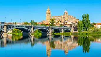 The Catedral Nueva and the Romanesque dome of the Catedral Vieja above the Roman Bridge over the Tormes River, Salamanca