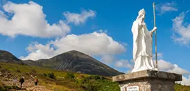 The statue of St. Patrick at the foot of Croagh Patrick, with pilgrims on the path