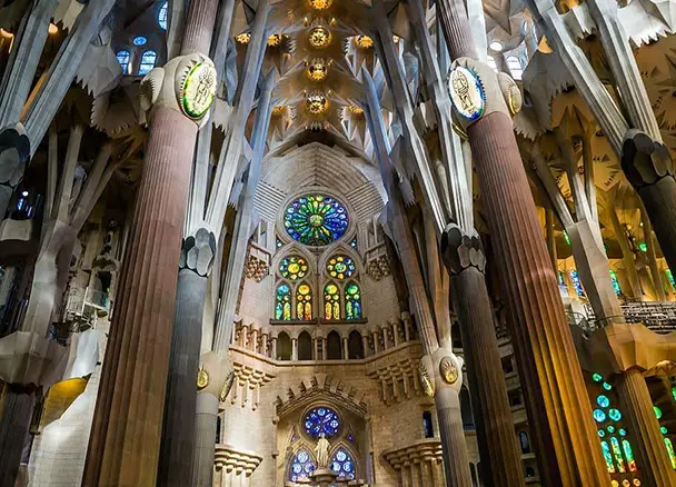 Tree-like branching columns inside the Sagrada Familia, looking up into the canopy of vaults lit by stained-glass windows