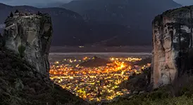 The town of Kalambaka at night beneath the illuminated Meteora rock formations, Greece
