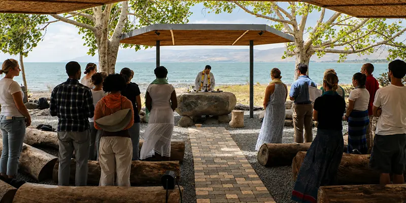 A priest leading his parish group in prayer at a pilgrimage site.