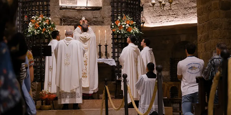 A priest celebrating Mass at a stone altar in the Basilica of Saint Francis in Assisi