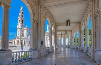 Colonnade of the Sanctuary of Fátima with the basilica bell tower beyond — Marian shrines pilgrimage