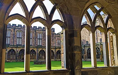 Gothic arches of the Durham Cathedral cloister looking across the green garth to the Norman stonework beyond