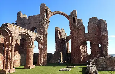 The rainbow arch and ruined nave of Lindisfarne Priory on Holy Island, where St. Aidan founded a monastery in 635