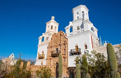 Mission San Xavier del Bac near Tucson, Arizona, with saguaro cactus against a clear sky — United States pilgrimage