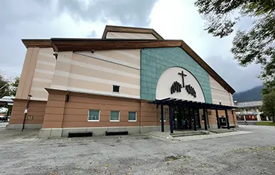 Exterior of the Oberammergau Passion Play Theater (Passionstheater), with its teal gabled facade and cross emblem above the entrance