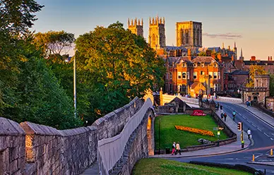 York Minster's towers rising above the rooftops at sunset, seen from York's medieval city walls