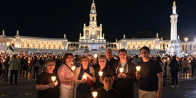 Pilgrims holding candles with their priest during the candlelight Rosary procession at Fatima